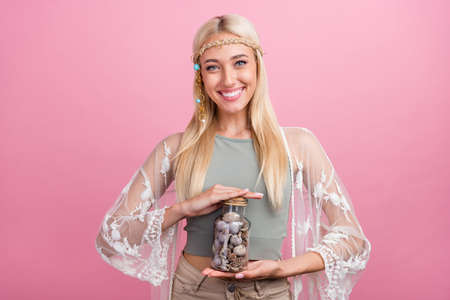 Photo of funky young blond lady hold shelves wear accessories top cape isolated on pink color backgroundの写真素材