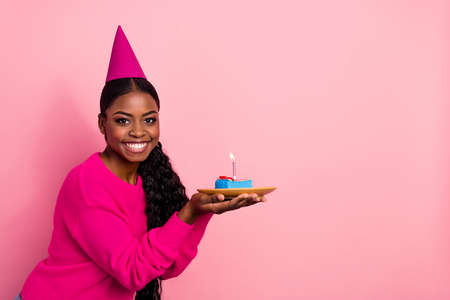 Photo of nice young brunette lady hold cake wear cap pullover isolated on pink color background