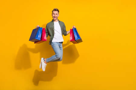 Full length body size view of attractive lucky guy jumping holding things having fun isolated over...