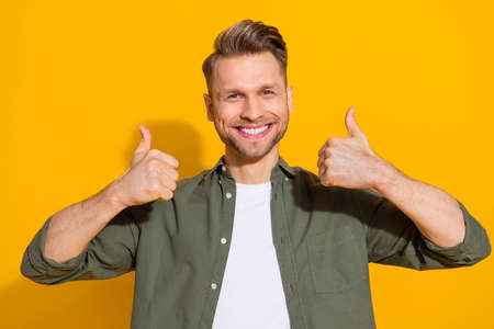 Portrait of attractive cheerful content guy showing double thmbup isolated over bright yellow color...