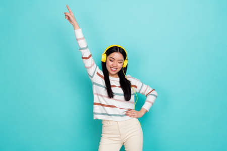 Photo of cute millennial lady listen music dance wear headphones sweater pants isolated on turquoise color backgroundの写真素材