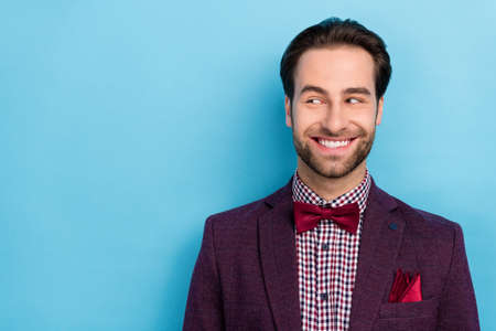 Portrait of cheerful thoughtful showman in tuxedo look empty space see promotion isolated on blue color backgroundの写真素材