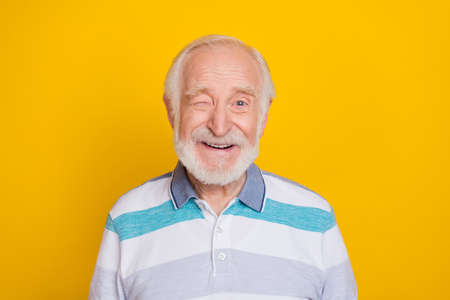 Portrait of attractive cheerful funny grey haired man smiling friendly winking isolated over vivid...