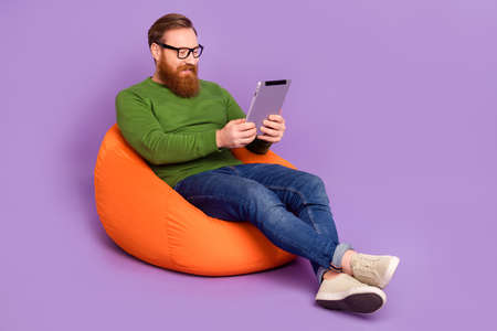 Full length portrait of positive cheerful person sit big bag use tablet write email isolated on...