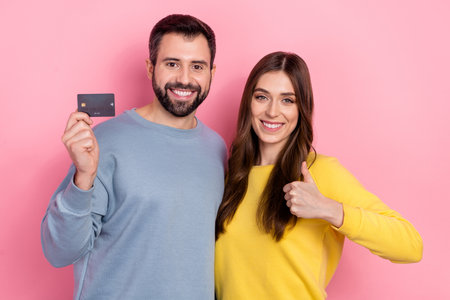 Portrait of beautiful handsome cheery friends friendship showing thumbup bank card isolated over...