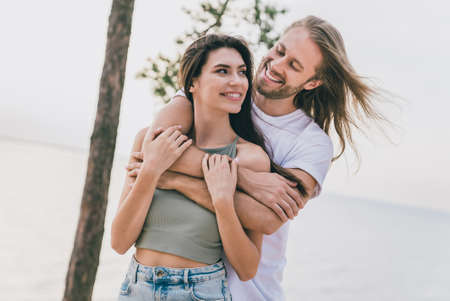 Photo of shiny cute husband wife walking cuddling enjoying summer time outdoors ocean seasideの写真素材