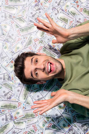 High angle view vertical portrait of impressed positive man raise hands isolated on money background