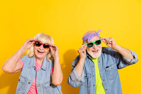 Photo of cool excited husband wife wear jeans shirts hands arms sunglass empty space isolated yellow color backgroundの写真素材