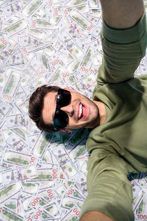 Above view vertical photo of cheerful excited person take selfie laying cashback isolated on money...