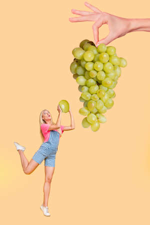 Vertical composite portrait of impressed person cut grape hanging huge hand isolated on beige color backgroundの写真素材