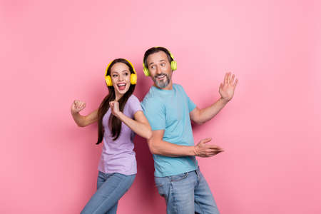 Photo of two excited crazy people enjoy listen favorite song dancing isolated on pink color backgroundの写真素材