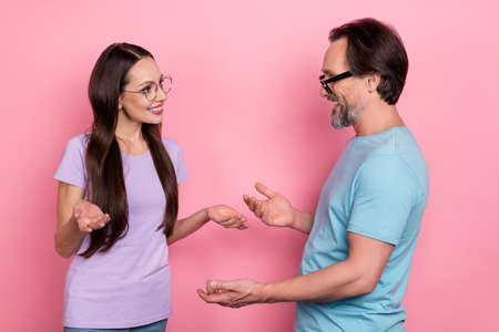 Photo of two cheerful positive partners communicate discuss chatting isolated on pink color backgroundの写真素材