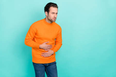 Portrait of unsatisfied person arm on stomach closed eyes feel bad isolated on teal color backgroundの写真素材