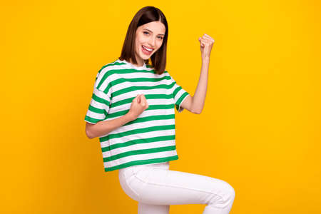 Photo of cool brunette millennial lady hands fists yell wear green t-shirt isolated on yellow color...