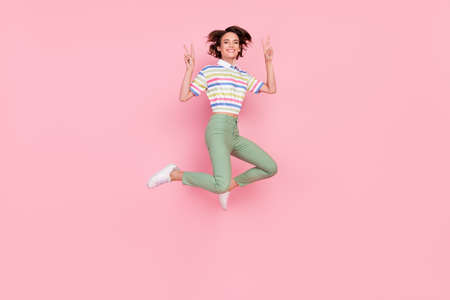 Full length photo of young girl happy positive smile show peace cool v-sign isolated over pink color...