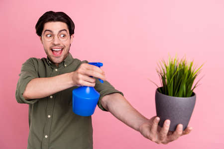 Photo of young amazed happy crazy cheerful man shoot water home plant pot isolated on pink color backgroundの写真素材