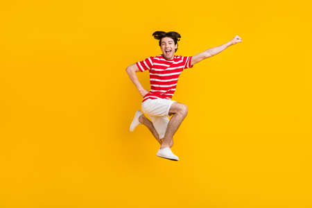 Full body photo of happy joyful young raise hand super hero jump up summer isolated on yellow color backgroundの写真素材