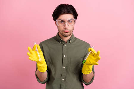Photo of confident guy hold two chemical tube wear goggles gloves khaki shirt isolated pink color backgroundの写真素材