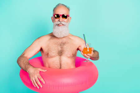 Photo of old man drink juice cocktail toothy smile wear rubber circle sunglass shorts isolated teal color backgroundの写真素材