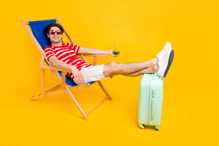 Photo of sweet charming man wear striped t-shirt sitting deck chair enjoying beverage smiling...