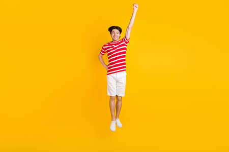 Full length photo of happy cheerful young raise hand super hero launch jump up isolated on yellow...