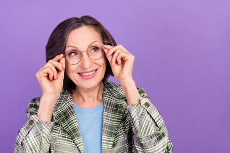 Photo of old happy cheerful woman look empty space wear glasses good mood isolated on violet color backgroundの写真素材