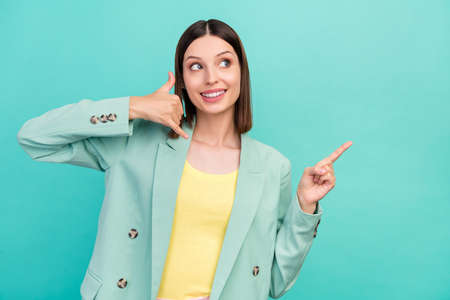 Portrait of cheerful attractive lady look indicate finger empty space isolated on teal color backgroundの写真素材
