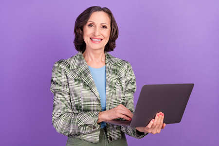 Photo of positive nice old woman business hold hands laptop vintage blazer isolated on violet color...