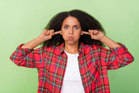 Photo of young attractive african woman fool cover fingers ears hold breath isolated over green color backgroundの写真素材