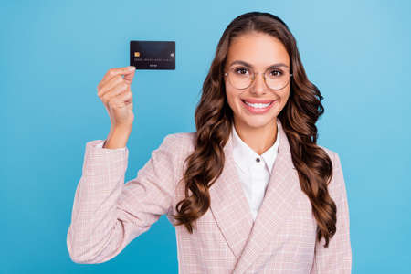 Portrait of attractive cheerful woman banker economist holding bank card bonus isolated over bright blue color backgroundの写真素材