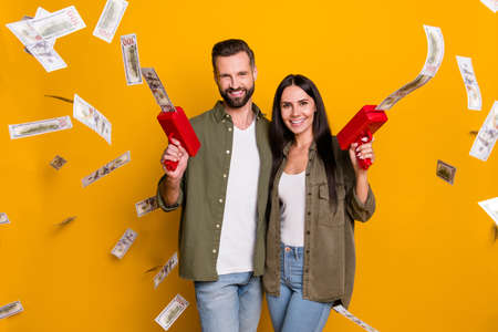 Photo of young cheerful husband wife shoot money benefit profit isolated over yellow color...