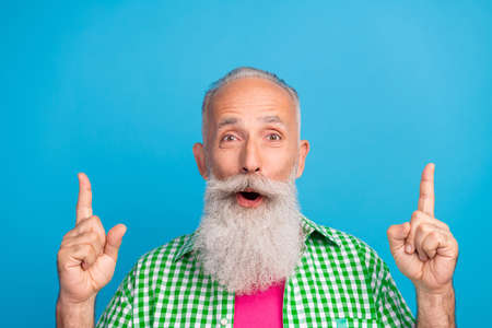 Photo of crazy astonished person direct fingers up empty space open mouth isolated on blue color...