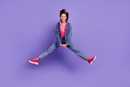 Full size photo of nice overjoyed young lady jumping toothy smile isolated on violet color backgroundの写真素材