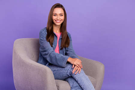 Photo of young satisfied gorgeous lady sitting chair toothy beaming smile isolated on violet color backgroundの写真素材