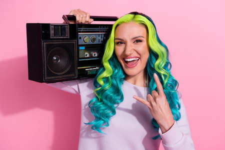 Portrait of careless positive girl hold boombox hand fingers demonstrate heavy metal symbol isolated on pink color backgroundの写真素材