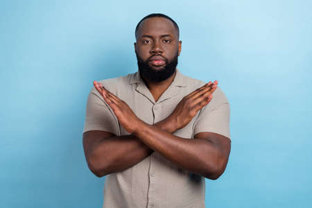 Portrait of confident focused handsome person crossed arms show stop gesture isolated on blue color backgroundの写真素材