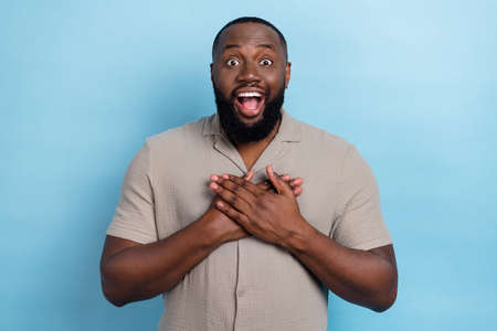 Portrait of positive person arms touch chest open mouth impressed reaction isolated on blue color backgroundの写真素材