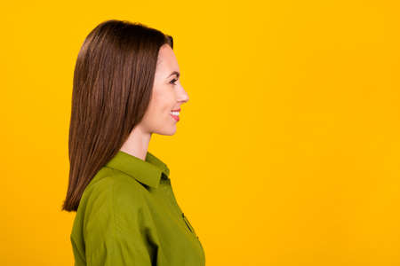 Photo of pretty charming young woman dressed green shirt looking empty space smiling isolated yellow color backgroundの写真素材