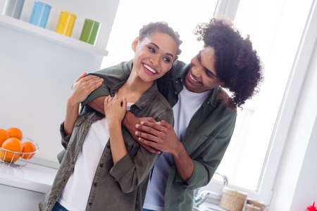 Photo of happy positive lovely girlfriend and boyfriend spend time together in kitchen room hug...