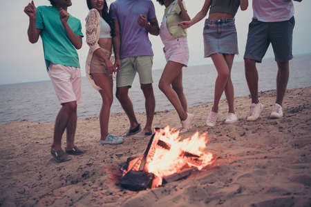 Cropped full length body size view of attractive carefree guys buddy fellow dancing around bonfire on beach outdoorsの写真素材