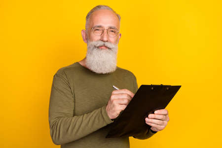 Photo of client old man hold clipboard sign contract wear specs green shirt isolated yellow color...