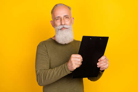 Portrait of attractive experienced grey-haired man holding in hands clipboard isolated over bright...