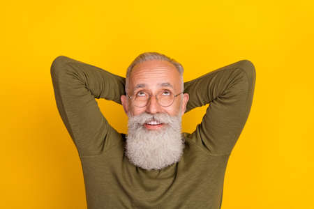 Photo of relaxed old man look up empty space dream wear eyewear green shirt isolated yellow color...