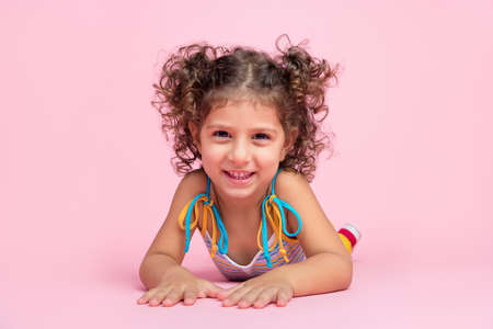 Portrait of attractive cheerful playful funny wavy-haired girl lying on floor good mood rest isolated over pink pastel color backgroundの写真素材
