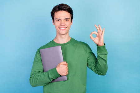 Photo portrait young guy keeping laptop showing okay gesture smiling isolated pastel blue color...