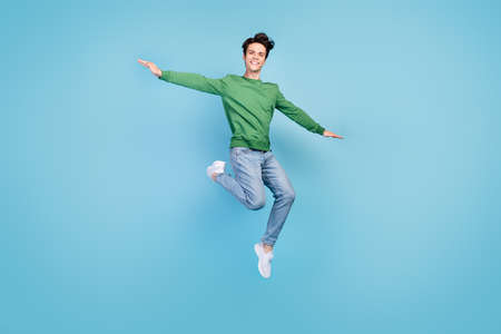 Full length body size photo guy jumping high careless playful smiling isolated pastel blue color backgroundの写真素材