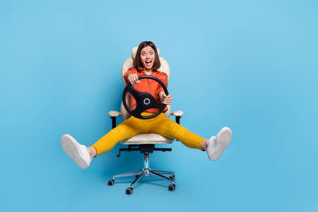 Portrait of attractive crazy cheerful girl in armchair riding vehicle having fun isolated over...