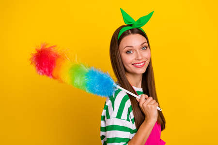 Profile portrait of cheerful positive girl hold duster toothy smile isolated on yellow color backgroundの写真素材