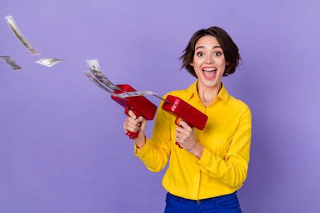 Photo of impressed millennial lady yell shoot money gun wear yellow shirt trousers isolated on...