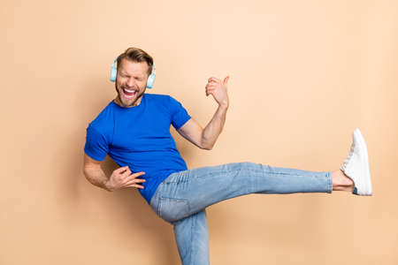Photo of cheerful overjoyed person enjoy playlist hands playing imagine guitar isolated on beige...
